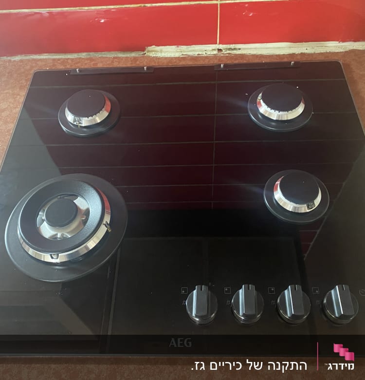 כיריים גז שחורות עם ארבעה מבערים וכפתורי שליטה